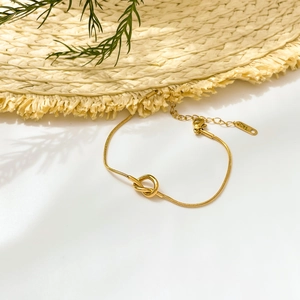 Detail of gold snake chain bracelet with knot design and K18 hallmark on white background
