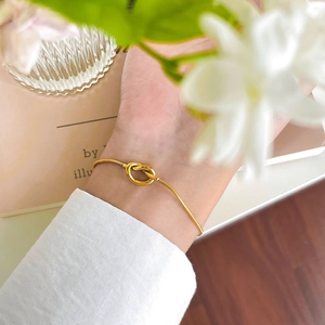 Elegant gold snake chain bracelet with daisy knot design on woman wrist