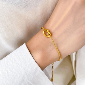 Detail of gold knot snake chain bracelet with adjustable extender on a model's wrist