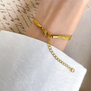 Detail of multi-strand gold chain bracelet with lobster clasp on vintage background