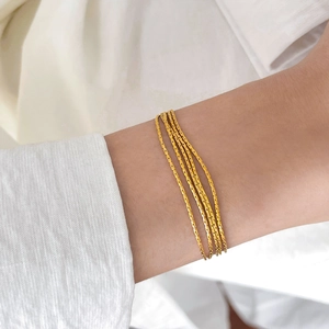 Detail of layered gold daisy chain bracelet on wrist showing the multi-strand link design