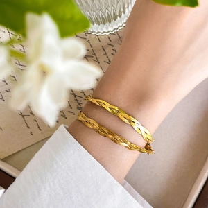 Detail of golden triple-layered braided snake chain bracelet on a woman's wrist