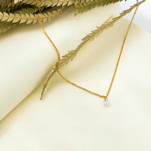 Gros plan du collier minimaliste doré avec zircon rond sur une page de livre esthétique