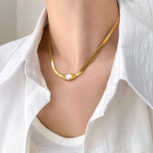 Détail d'un collier chaîne serpent dorée avec un seul zircon scintillant sur un modèle