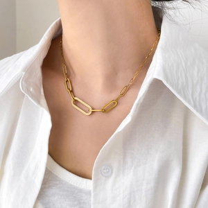 Gros plan d'un collier doré à gros maillons sertis de zircons sur une chemise