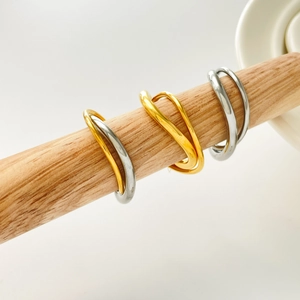 Close-up of dual-layer wavy beaded rings in gold and silver finish on wooden stand