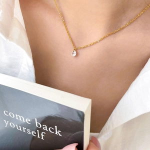 Gros plan du collier minimaliste en or avec zircon porté avec une chemise blanche