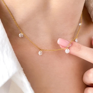 Gros plan d'un collier doré avec pendentifs en zircon sur le cou d'un modèle