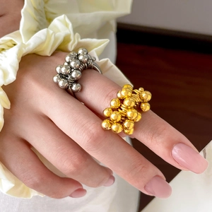 Close-up of dual-tone 18K gold and silver titanium steel beaded wave rings on a model