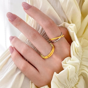 Detail of two-tone layered wavy rings worn by model on a soft fabric background