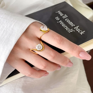 Bague ouverte en acier doré avec zircons poire et rond portés par un mannequin