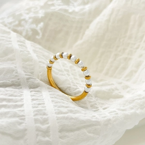 Close-up of elegant freshwater pearl ring with gold bead accents on textured cloth