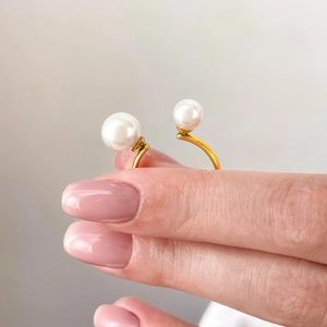 Close-up of gold titanium steel open ring featuring two elegant white pearls
