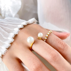 Close-up of gold titanium pearl rings on hand with elegant white chiffon sleeve accents
