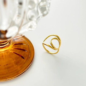 Gros plan détaillé d'une bague géométrique évidée en or sur une surface blanche épurée