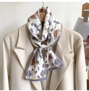 Detail of floral silk scarf with purple trim styled on a beige suit blazer