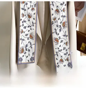 Close-up of floral silk skinny scarf draped on a beige blazer for office styling