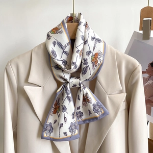 Silk-like long scarf with orange floral prints styled on a beige blazer jacket