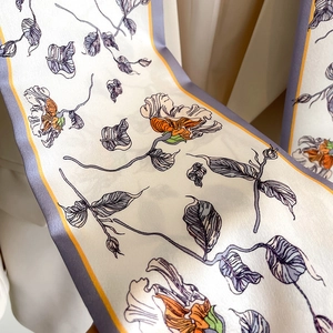 Detail of silk scarf with purple floral pattern and elegant orange accents