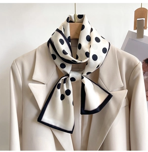 Close-up of a polka dot silk scarf styled as an elegant tie on a white blazer