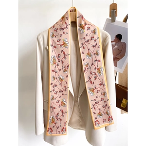 Elegant floral silk skinny scarf in pink and orange tied on a beige blazer lapel