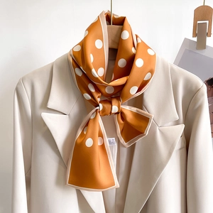 Polka dot silk scarf in orange draped on a beige blazer collar for a French look