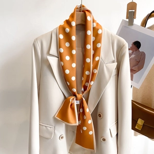 Polka dot skinny orange silk scarf tied on a beige blazer as a stylish neck accessory