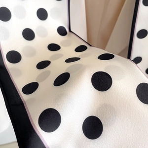 Detailed close-up of polka dot silk scarf featuring contrast black borders and purple lines