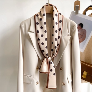 Elegant polka dot skinny silk scarf in beige and brown tied on a blazer lapel