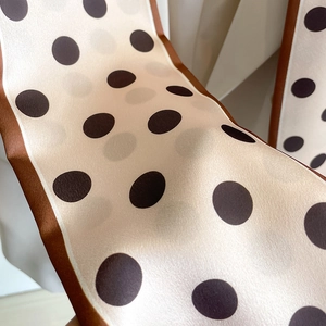 Detail of silk-like champagne scarf with brown polka dots and delicate edge stitching
