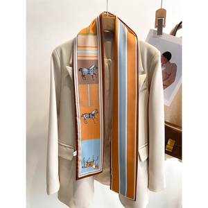 Detail of equestrian silk scarf with orange stripes styled on a chic blazer