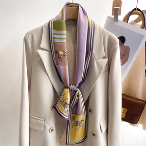 Close-up of silk twilly scarf with horse print tied to a white blazer lapel
