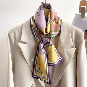 Classic patterned narrow silk scarf with horse and plaid design tied on a cream blazer
