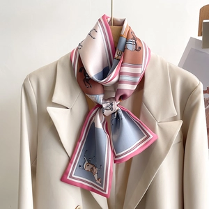 Close-up of narrow silk scarf with horse print tied on a beige suit collar