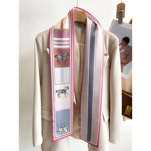 Close-up of a long skinny silk scarf with horse prints on a beige blazer lapel