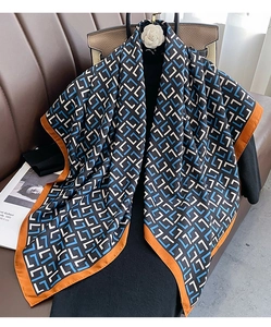 Close-up of luxury geometric pattern silk scarf with vibrant orange border on a mannequin