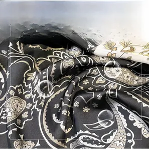 Close-up of silky paisley pattern fabric with golden and white details on black satin