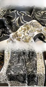 Macro detail of faux silk scarf showing paisley pattern texture and fine hemmed edges