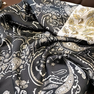 Macro shot of paisley and floral silk scarf showing premium draping and glossy texture