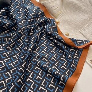 Silk-textured square scarf with blue and black geometric pattern and orange borders