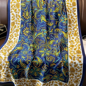 Detailed texture of paisley silk scarf with gold borders on elegant blue fabric