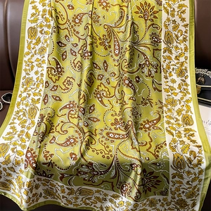 Detail of silk-like scarf with green paisley floral print and smooth hemline texture