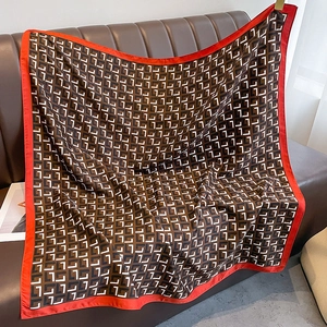 Detail of silk scarf with geometric hook pattern and red border on leather background