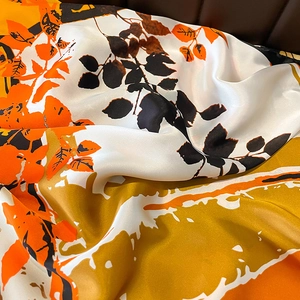 Satin silk scarf with vibrant orange leaf patterns showing smooth texture and drapes