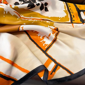 Macro detail of silk scarf showing geometric orange floral patterns and smooth texture