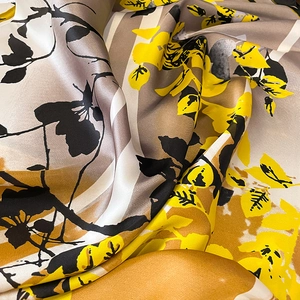 Close-up of floral silk scarf showing yellow and black leaf patterns and satin texture