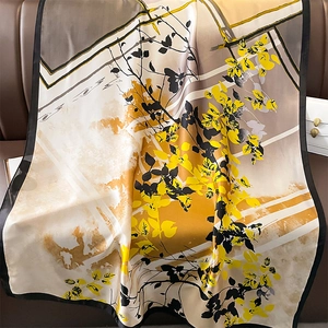 Detailed view of art leaf print on large silk square scarf draped on leather sofa
