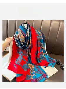 Detailed view of red and blue silk scarf with golden floral patterns on knitwear
