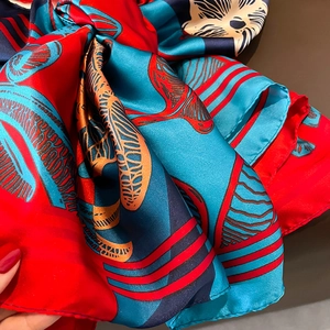 Elegant silk-like scarf with artistic red and blue patterns, luxurious soft draped fabric
