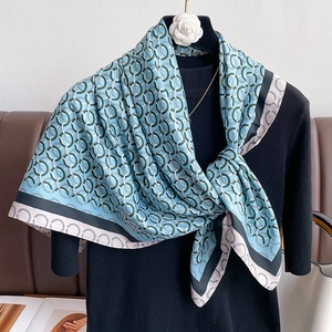 Elegante scialle di seta azzurro con motivo a catena geometrica su un manichino